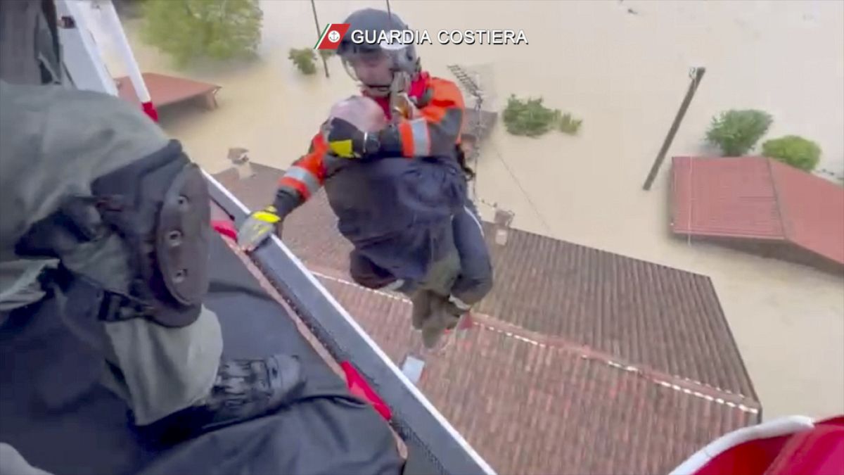 Un guardacostas desciende de un helicóptero para rescatar a un hombre sobre un tejado, en Faenza