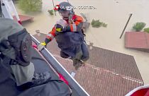 Un guardacostas desciende de un helicóptero para rescatar a un hombre sobre un tejado, en Faenza