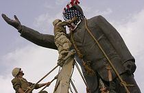 ABD'li asker, 9 Nisan 2003'te Irak'ın başkenti Bağdat'ta Saddam Hüseyin'in heykelini devirmeden önce heykelin yüzünü Amerikan bayrağıyla kapatıyor.