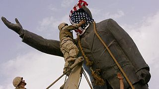 A statue of Saddam Hussein with an American flag before toppling in downtown Baghdad, Iraq, on April 9, 2003. C