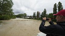 A man photographs the swollen Santerno River with behind the Enzo e Dino Ferrari circuit, in Imola, Italy, Wednesday, May 17, 2023.