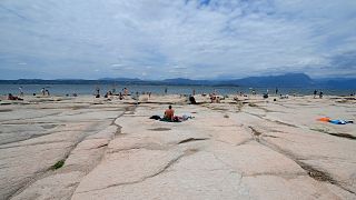 People sunbath on the peninsula of Sirmione, on Garda lake, Italy, Friday, Aug. 12, 2022.