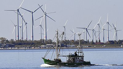 A fishing boat passes wind turbines between the island Langeoog and Bensersiel off the North Sea coast in Germany