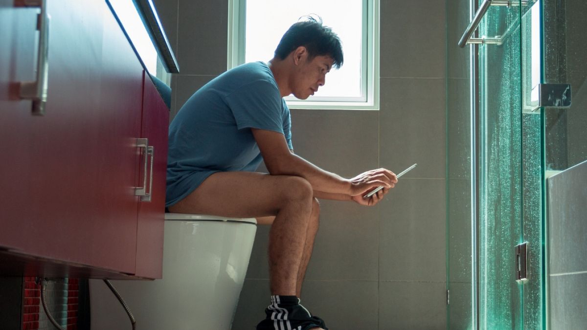 A man sitting on the toilet. 