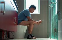A man sitting on the toilet. 