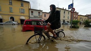 A cyclist rides through a flooded street in the village of Castel Bolognese, Italy, Wednesday, May 17, 2023
