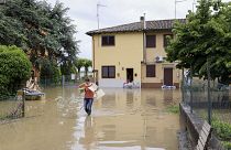 Eine Frau trägt ihre Habseligkeiten in einem überfluteten Gebiet in der Nähe von Bologna, Italien, Donnerstag, 18. Mai 2023