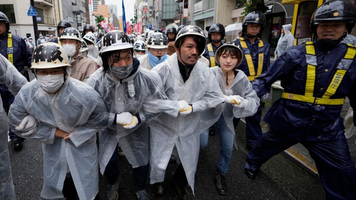 Demonstrierende marschieren durch die Straßen von Hiroshima, umgeben von Polizisten, während eines Protests gegen den G7-Gipfel