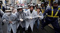 Demonstrierende marschieren durch die Straßen von Hiroshima, umgeben von Polizisten, während eines Protests gegen den G7-Gipfel