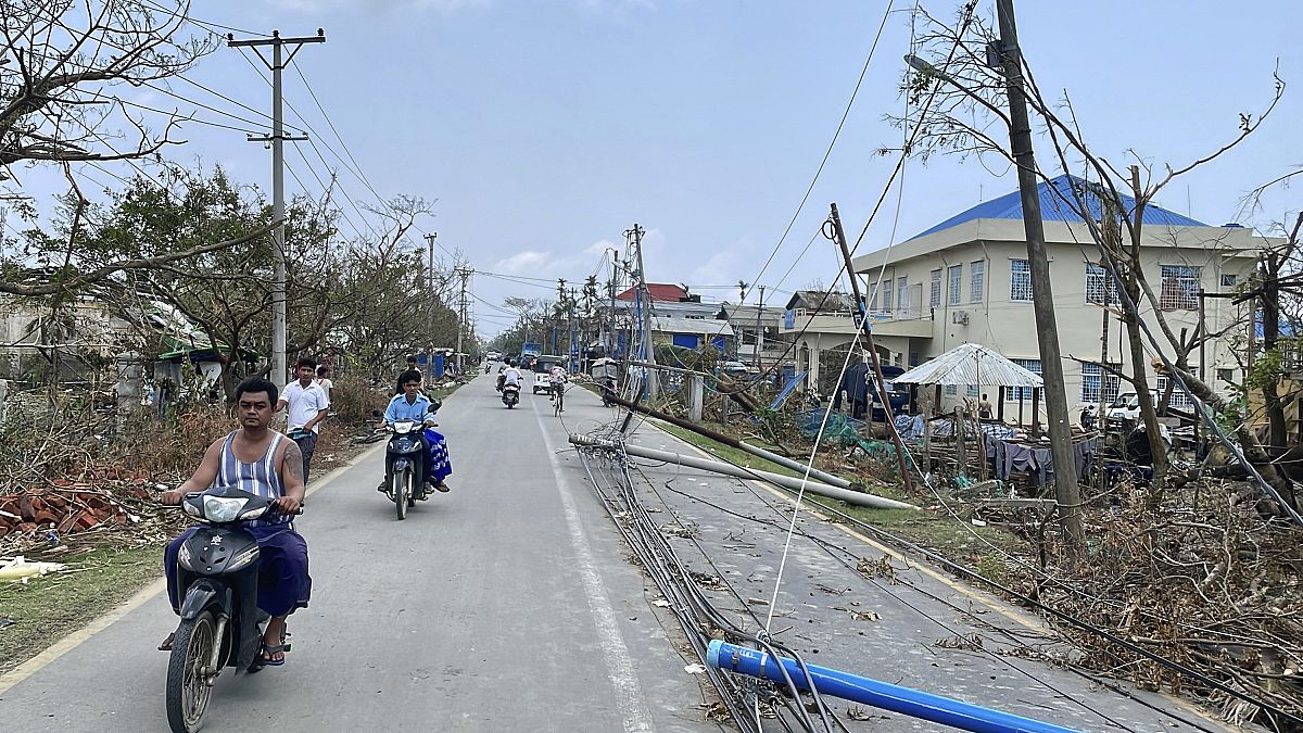 راكبو دراجات نارية بالقرب من أعمدة إنارة مدمرة إثر إعصار موكا في بلدة سيتوي، ميانمار.