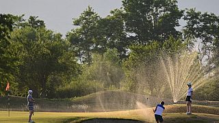 French golfers play in front of active water sprinklers in Rouffach, eastern France, on June 15, 2022.