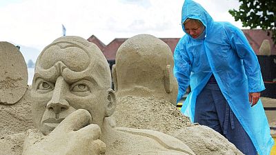 Kirsten Andersen from Denmark braves the rainy weather as she works at her sand sculpture titled "a new perspective on planet earth".