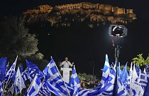 Supporters wave Greek flags as Greece's Prime Minister and New Democracy leader Kyriakos Mitsotakis gestures during his main election campaign rally in Athens.