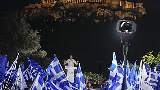 Supporters wave Greek flags as Greece's Prime Minister and New Democracy leader Kyriakos Mitsotakis gestures during his main election campaign rally in Athens.
