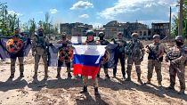 فرمانده گروه واگنر با پرچم روسیه در کنار سربازان مزدور با پرچم واگنر به تاریخ بیستم مه ۲۰۲۳ در شهر باهموت