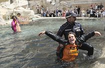 Ein Beamter holt eine Frau aus dem Trevi-Brunnen, die offenbar zur Gruppe "Letzte Generation" gehört. 