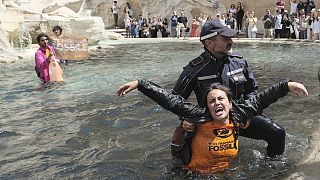 Last Generation environmentalists are being taken out after showing a banner against the use of fossil fuels in the Trevi Fountain in Rome, Sunday, May 21, 2023.