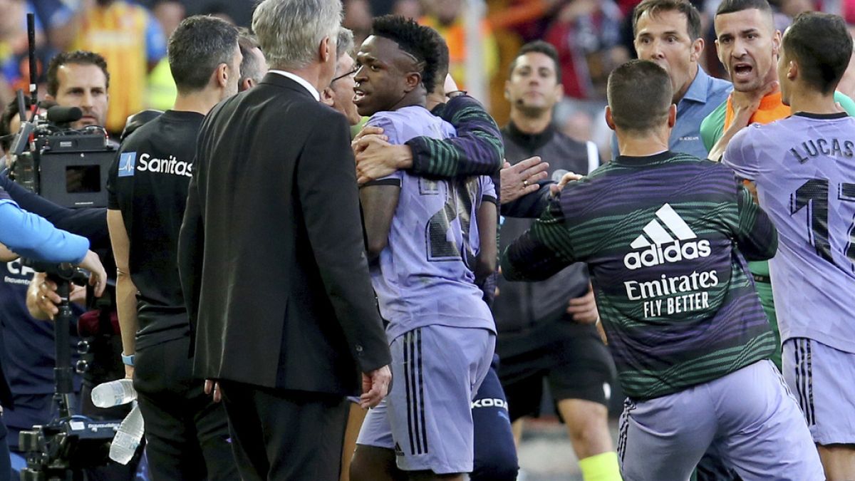 El jugador del Real Madrid Vinicius Junior, en el centro, camina junto al entrenador Carlo Ancelotti, delante a la izquierda, después de ser expulsado del campo