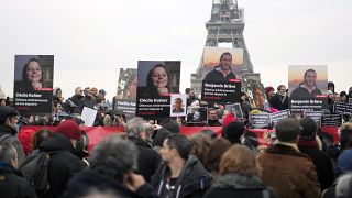 People hold portraits of French hostages in Iran Cecile Kohler, left, and Benjamin Briere during a protest in Paris, Saturday, Jan. 28, 2023. 