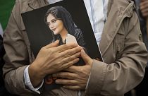 Mahsa Amini portréja egy iráni tüntető kezében