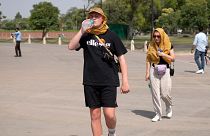 A foreign tourist drinks water in New Delhi, India, as sizzling temperatures breached normal levels, 23 May 2023.