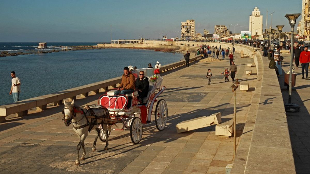 أشخاص يركبون عربة تجرها الخيول على طول كورنيش الواجهة البحرية في بنغازي شرق ليبيا، 26 مارس 2023 .