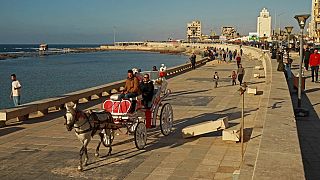 أشخاص يركبون عربة تجرها الخيول على طول كورنيش الواجهة البحرية في بنغازي شرق ليبيا، 26 مارس 2023 .