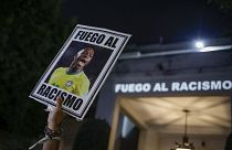 Un manifestante sostiene una foto de la estrella del fútbol brasileño Vinicius Jr y un mensaje en portugués; "Lucha contra el racismo"