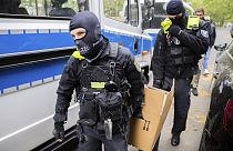 Des policiers transportent un carton vers un véhicule lors d'un raid à Berlin, Allemagne, mercredi 24 mai 2023. Christoph Soeder/dpa via AP