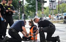 Police officers use hammers and chisels to remove a climate activist who has glued himself to a road during a climate protest in Berlin, Germany, 22 May 2023.