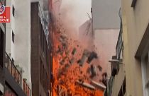 Una pared se derrumba mientras un gran incendio arrasa un edificio de siete plantas. 