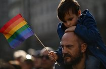 A man carries a boy on his shoulders during a demonstration by gay rights and civil society groups in Milan on March 18, 2023.