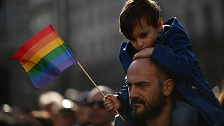 A man carries a boy on his shoulders during a demonstration by gay rights and civil society groups in Milan on March 18, 2023.