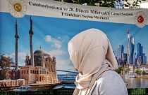 A Turkish woman goes to the polling station as she looks at a banner showing a Turkish mosque and the skyline of Frankfurt, Germany, Wednesday, May 24, 2023. 