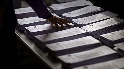 A woman picks a ballot paper for the general election in Barcelona, Spain, Sunday, Nov.10, 2019.
