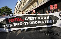 Des manifestants affichent une banderole "Total, vous êtes les éco-terroristes" avant l'AG des actionnaires deTotalEnergies,vendredi 26 mai 2023 à Paris.