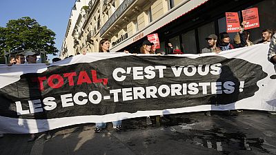 Des manifestants affichent une banderole "Total, vous êtes les éco-terroristes" avant l'AG des actionnaires deTotalEnergies,vendredi 26 mai 2023 à Paris.