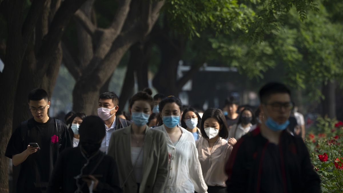 Maszkot viselő járókelők Peking üzleti negyedében