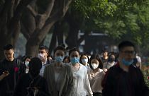 Maszkot viselő járókelők Peking üzleti negyedében