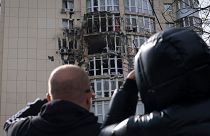 دو تن از ساکنان کی‌یف در حال نگاه کردن به آسیب‌های واره به یک ساختمان مسکونی پس از حملات پهپادی ۲۰ روز پیش (۸ مه ۲۰۲۳)