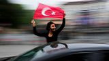 A supporter of the President Recep Tayyip Erdogan holds a Turkish flag outside his house in Istanbul, Turkey, Sunday, May 28, 2023.