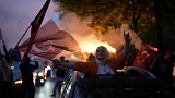 A supporter of the President Recep Tayyip Erdogan holds a Turkish flag outside his house in Istanbul, Turkey, Sunday, May 28, 2023.