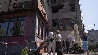 People look at an apartment building damaged by a drone during a night attack in Kyiv, Ukraine, May 28, 2023. 