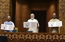Rajya Sabha Deputy Chairman Harivansh Narayan Singh, PM Narendra Modi and Lok Sabha Speaker Om Birla unveil coins marking the inauguration of the new parliament building.