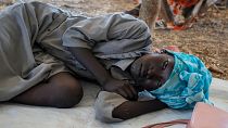 فتاة سودانية نازحة تنتظر عند معبر حدودي بين السودان وجنوب السودان