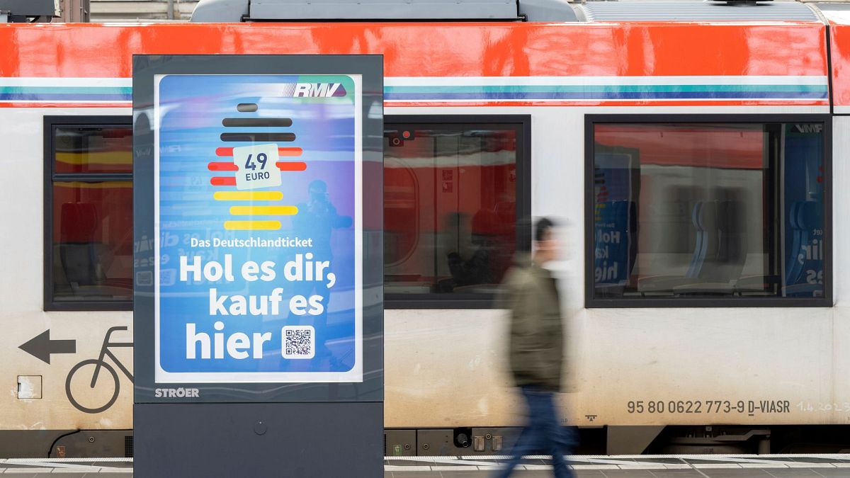 Un hombre pasa junto a un anuncio del Deutschlandticket (Billete de Alemania) en una estación de tren de Fráncfort, Alemania, el lunes 1 de mayo de 2023. 