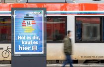 Мужчина проходит мимо рекламы немецкого билета (Deutschlandticket) на железнодорожном вокзале во Франкфурте, Германия, понедельник, 1 мая 2023 года. 