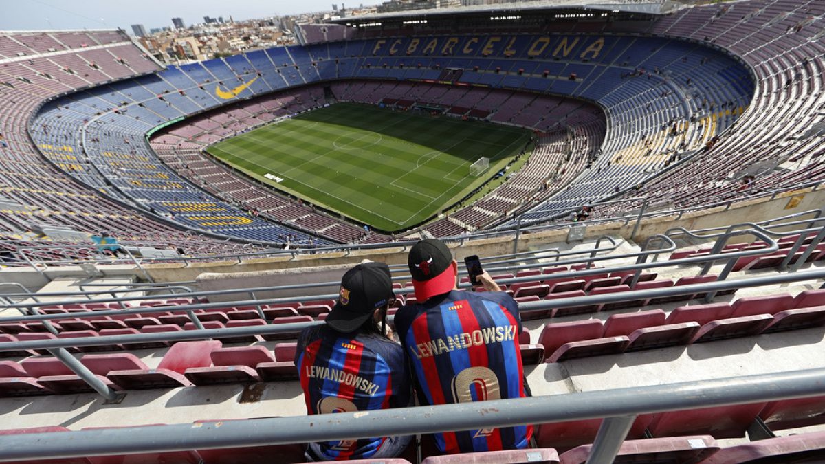 Two Barcelona fans wait for the start of a Spanish La Liga soccer match between Barcelona and Mallorca at the Camp Nou stadium in Barcelona