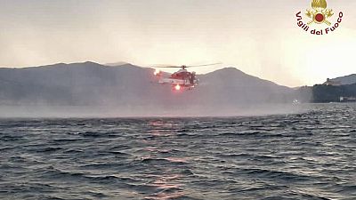 In this image released by the Italian firefighters a helicopter search for missing after a tourist boat capsized in a storm on Italy's Lago Maggiore in Lombardy region.