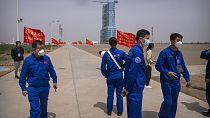 Staff members stand near the Shenzhou-16 spacecraft sitting atop a Long March rocket covered on a launch pad at the Jiuquan Satellite Launch Center in northwest China.